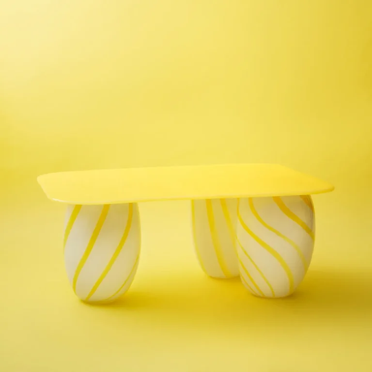 Yellow Candy Sofa Table by Studio Berg, yellow glass top on three white and yellow striped legs, on a plain background