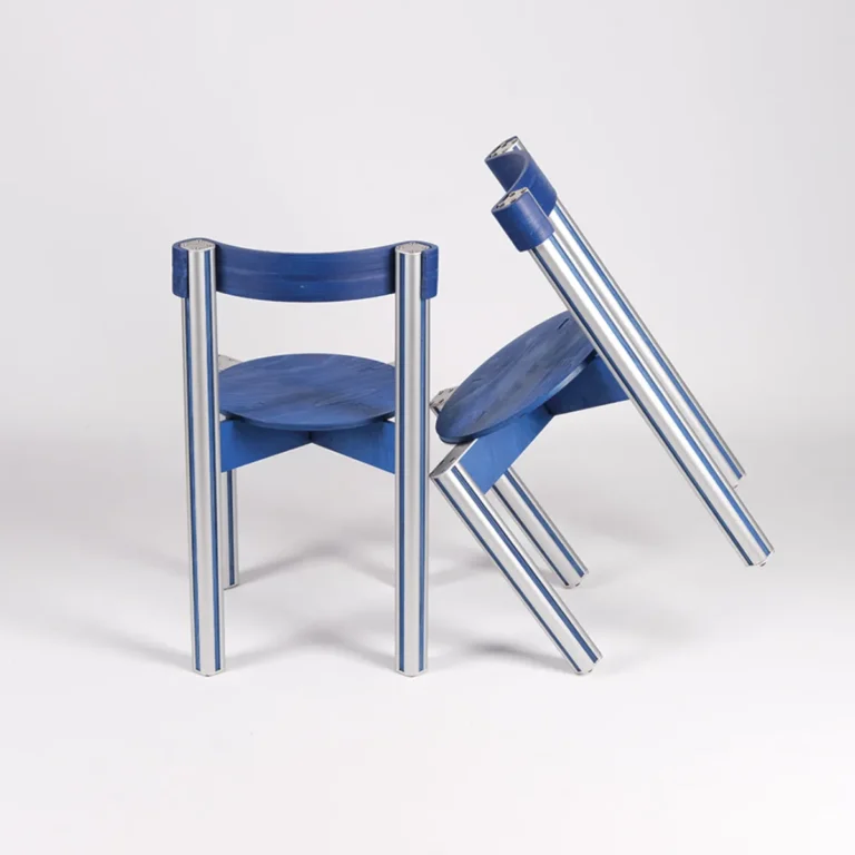 Sigma Chair by 301 Design Studio, one blue chair standing beside two others tilted and leaning against each other