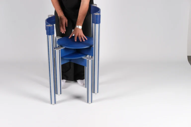 Sigma Chair by 301 Design Studio, a person pressing down on the seat of two blue chairs stacked together