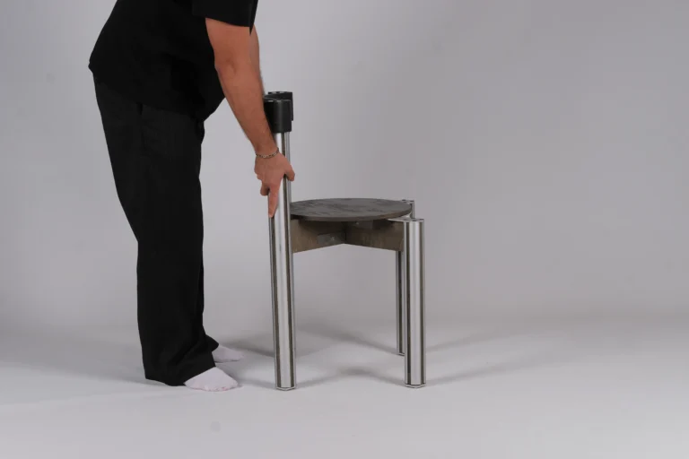 Sigma Chair by 301 Design Studio, a person in black holding the backrest post of a grey chair with aluminum legs