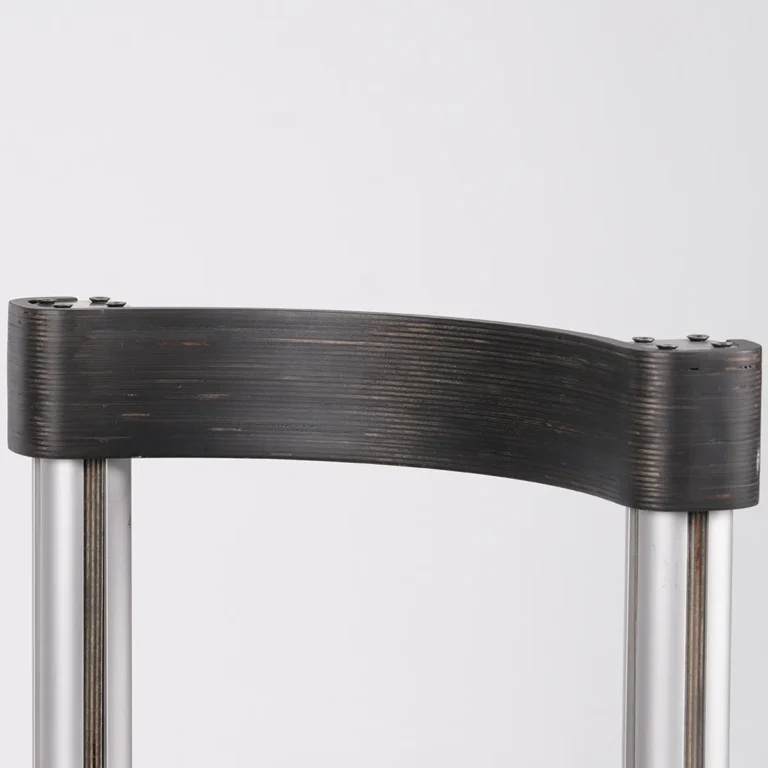 Close-up of the Sigma Chair's curved dark backrest, with visible plywood layers and screws atop aluminum posts