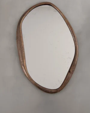 Perfumer Mirro Xl by Vogel Studio, bronze wall mirror with an organic pebble-shaped frame, on a plain grey wall