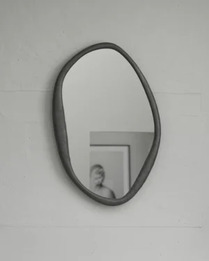 Mirror Perfumer by Vogel Studio, organic-shaped aluminium wall mirror with a dark grey frame on a white wall