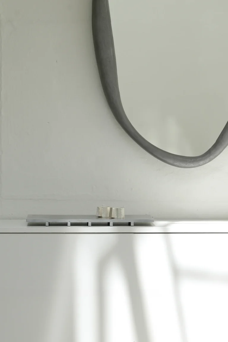 Mirror Perfumer by Vogel Studio in a bright room, hung above a shelf holding a metal tray and a small object