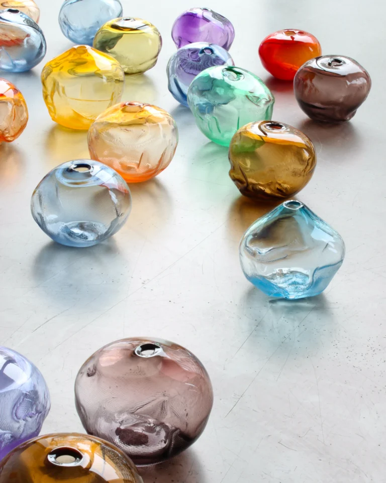 1 2 Ltr Forms by Vogel Studio among many glass forms in blue, purple, green, red and brown on a metal surface