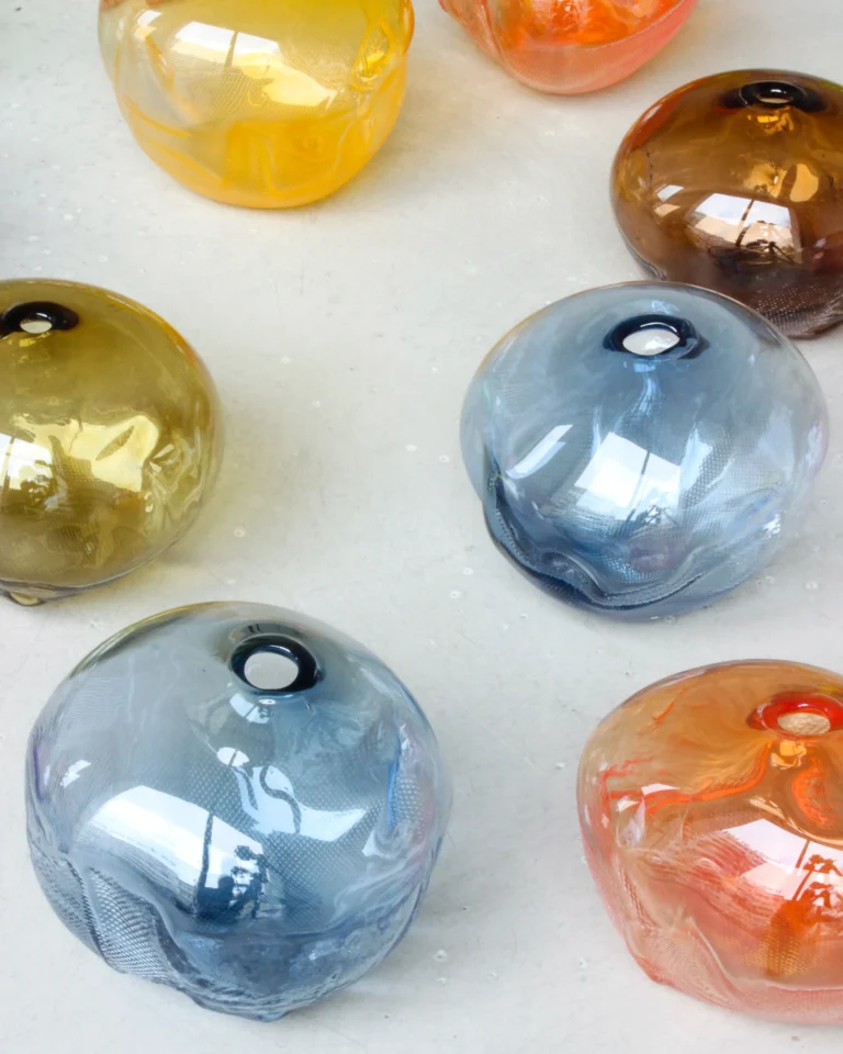 1 2 Ltr Forms by Vogel Studio, close view of glass forms in yellow, blue-grey, brown and orange on a pale surface