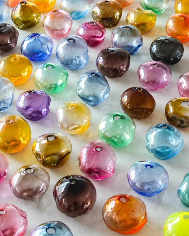 1 2 Ltr Forms by Vogel Studio, dense grid of small glass forms in pink, blue, green, brown and gold, seen from above