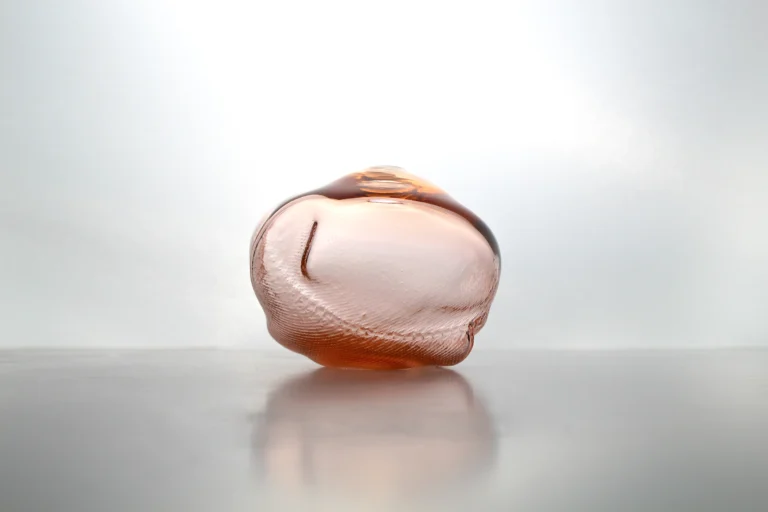 1 2 Ltr Forms Aurora Yellowish Handmade Glass Object by Vogel Studio resting on a reflective surface at eye level