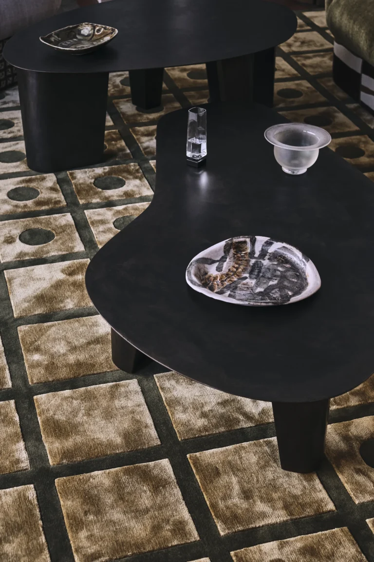 Paris Coffee Table by Vogel Studio seen from above, dark steel top holding a glass vase, a frosted bowl and a ceramic dish