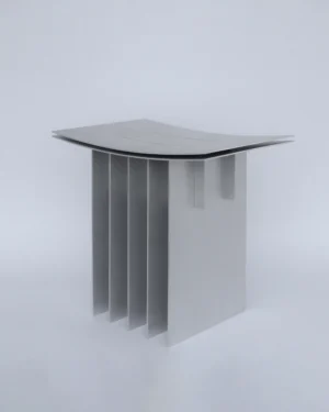 Brush Stool by SESTRA, aluminum stool with a curved double seat on parallel vertical fins, on a plain background