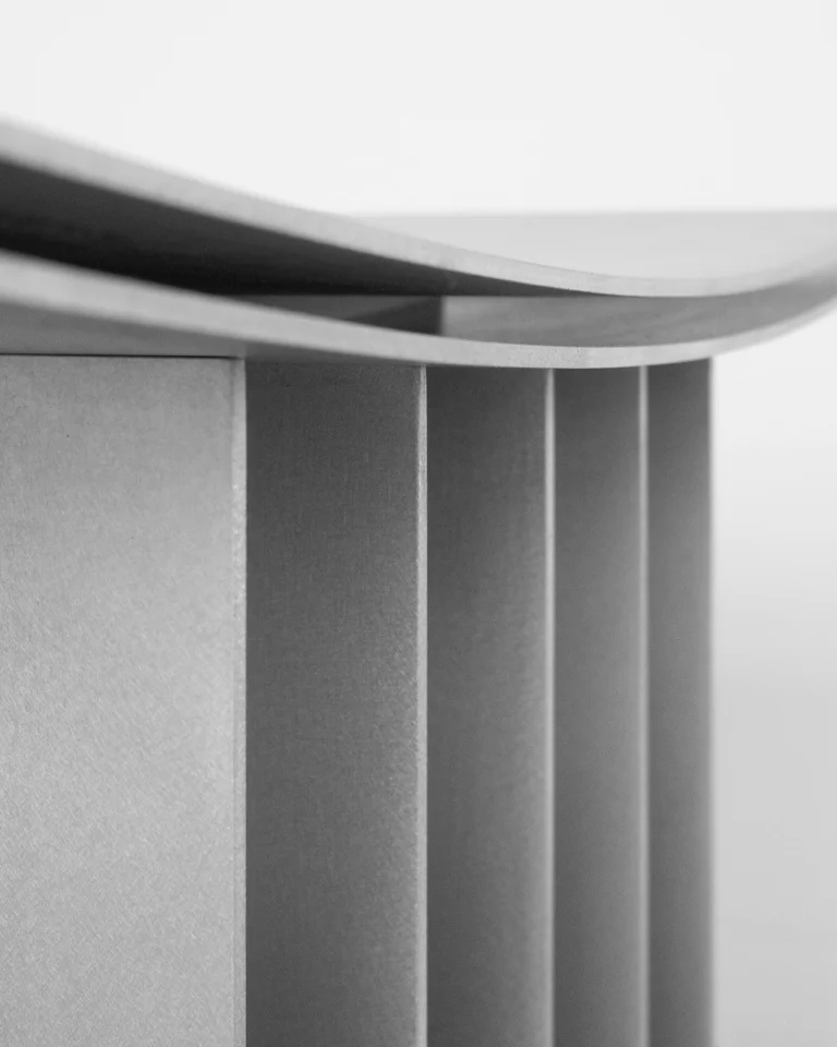 Close-up of the Brush Stool's layered curved seat edge above the row of matte aluminum fins