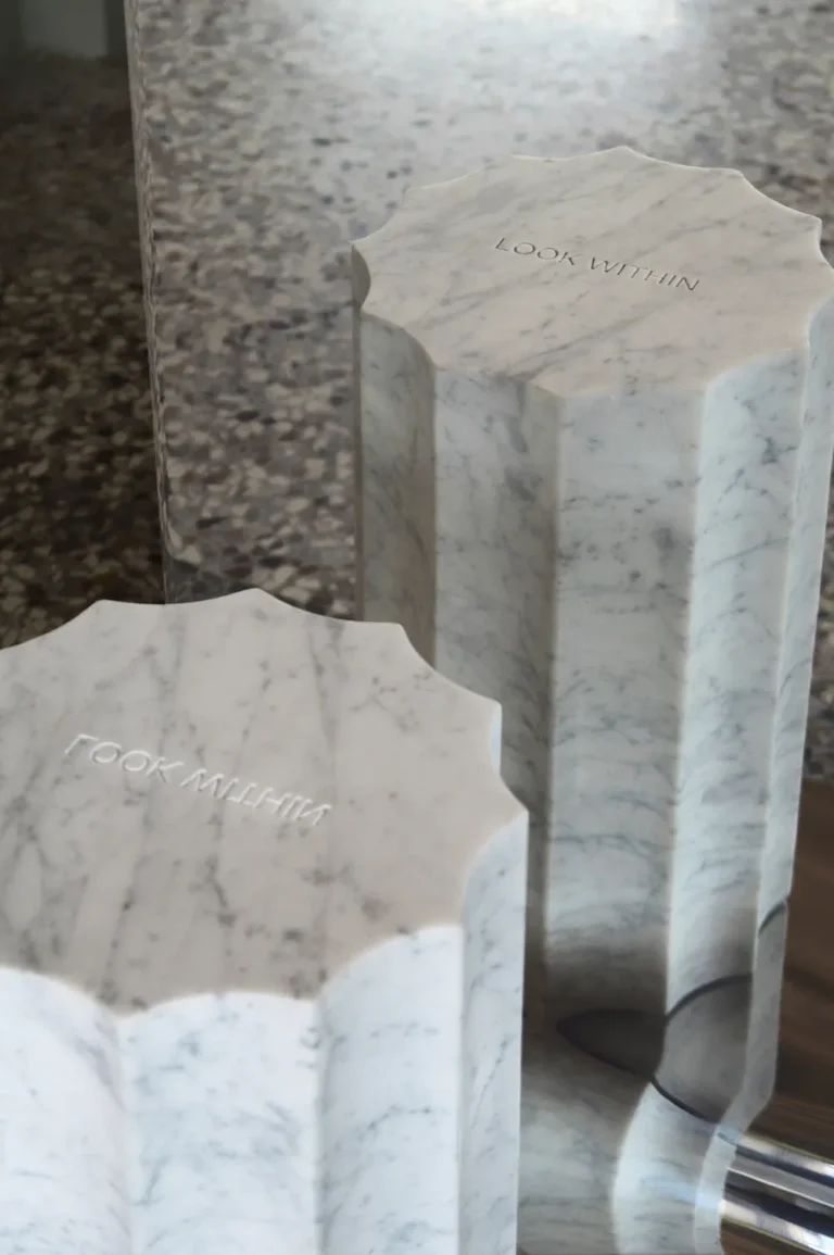 Close-up of the Meditations mirror's marble columns with engraved LOOK WITHIN, doubled in the polished steel surface