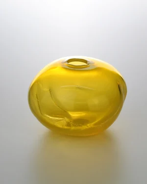 1 2 Ltr Forms by Vogel Studio, honey yellow blown glass object with a small opening, on a plain background