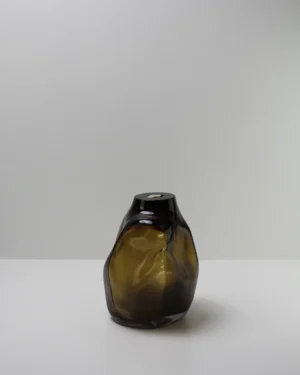105 Ltr Forms by Vogel Studio, olive green blown glass object with dented organic form, on a plain background