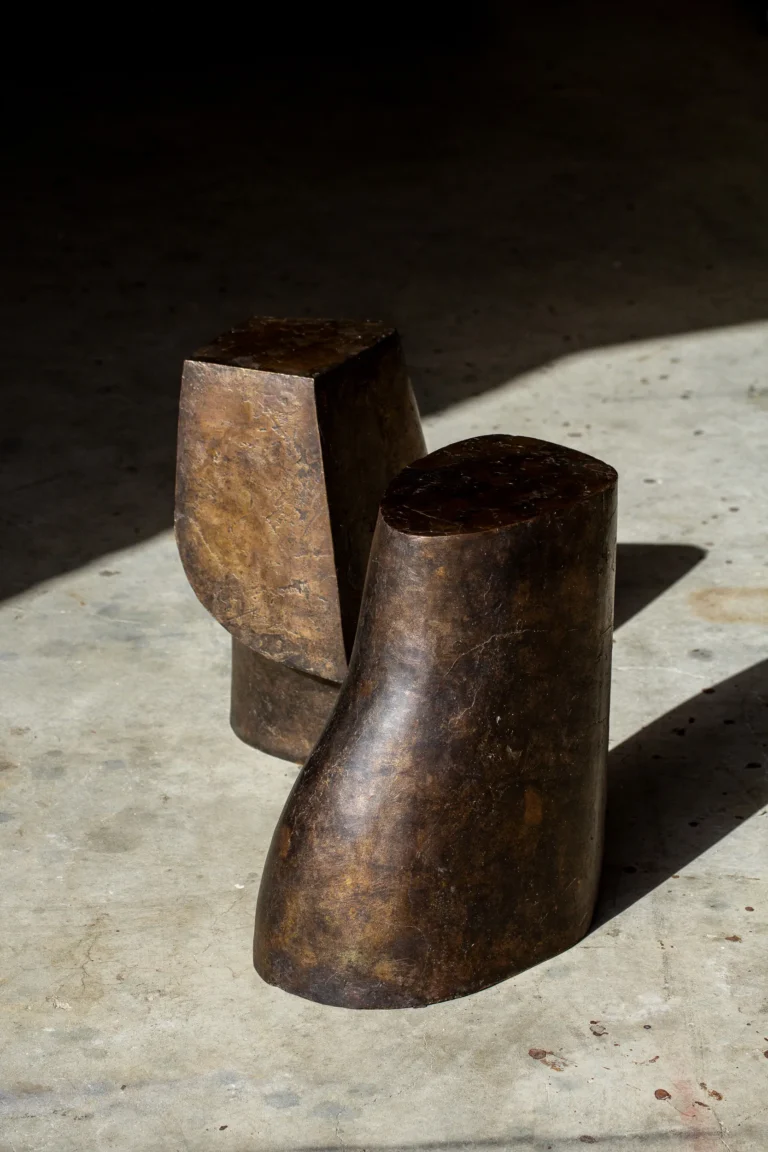 Palm Table I by Vogel Studio in dark, moody light, a dark patinated bronze table in front of a geometric companion