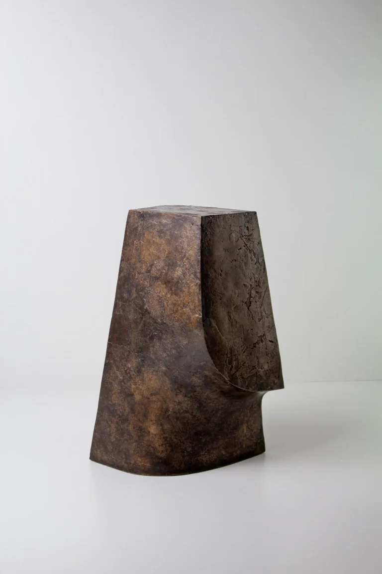 Palm Table Il by Vogel Studio, dark raw finish bronze side table with a mottled surface, on a plain background