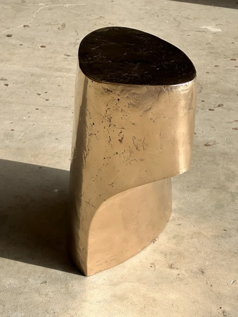 Palm Table I by Vogel Studio seen from the side, the bronze overhanging upper section and a stamped mark near the base