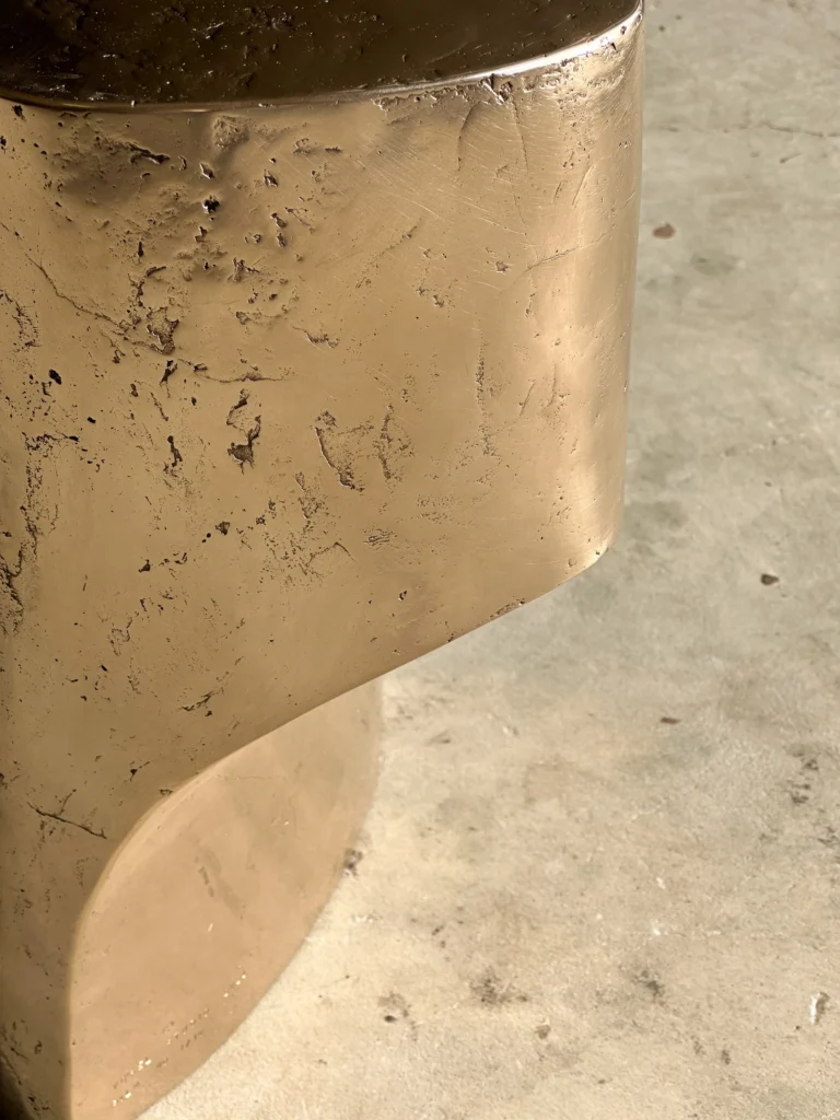 Close-up of the Palm Table I's cast bronze surface, with pitted texture and the curved step between upper and lower sections