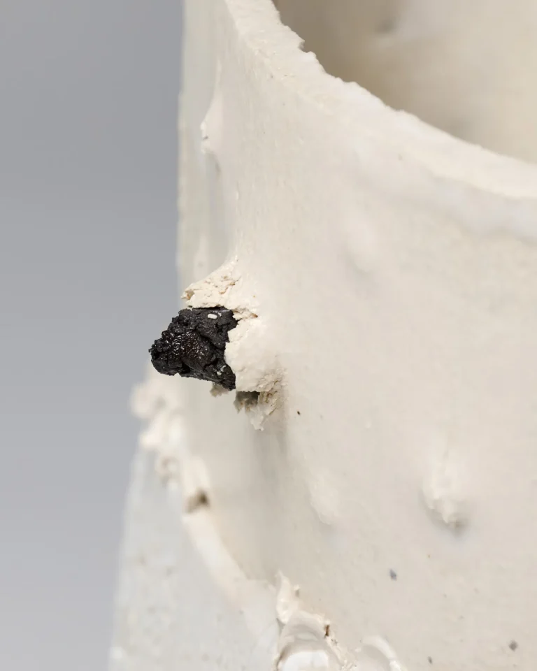 Close-up of the New_love_01 vase's rough white neck with a small black lump of glaze protruding from the surface